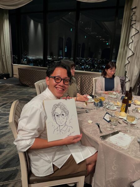 企業パーティーで完成した早描き似顔絵を手に笑顔のお客様