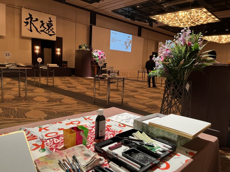 企業パーティーでテーブルを回りながら早描き似顔絵を描く似顔絵師・田村まりり
