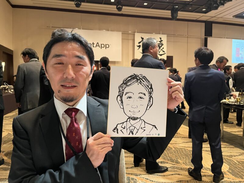 企業パーティーで完成した早描き似顔絵を手に笑顔のお客様
